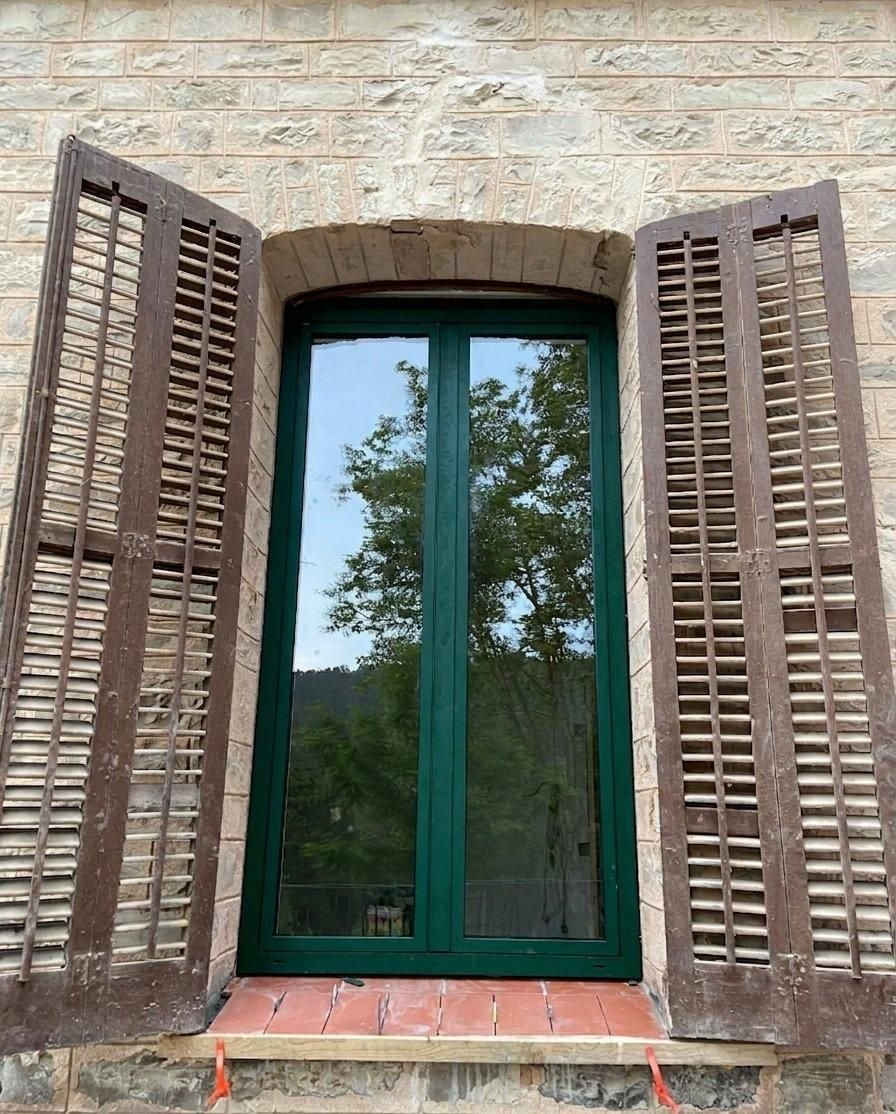Ventana de aluminio bicolor vista desde el exterior, integrada en una fachada de piedra